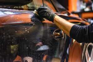 Home Professionele autopoetser gebruikt wax en poetsmiddel voor optimale glans op donkere auto